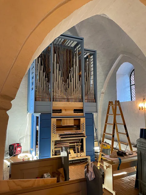 Orgel ses fra kirkerummet der er arbejdslys og stiger omkring det